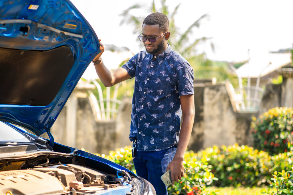 guy staring at his unreliable car engine with the hood up