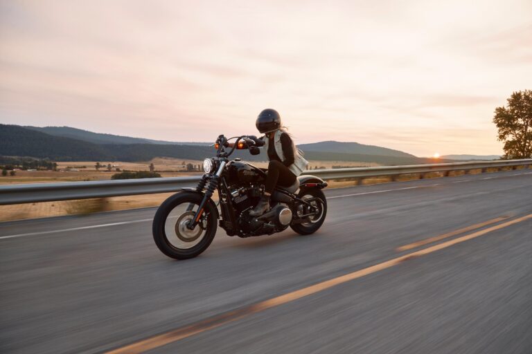 Rider on a cruiser motorcycle on an open highway at sunset