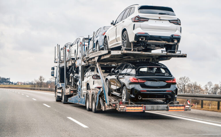 Two-level car carrier loaded with new SUVs driving down a highway