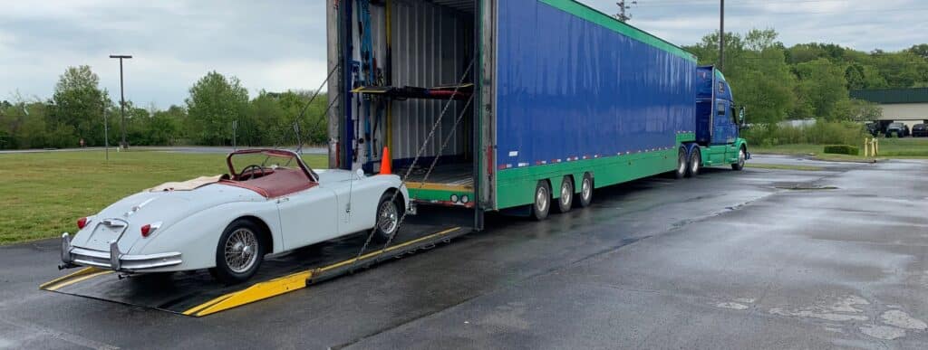 White classic roadster loading up the ramp of an enclosed car carrier